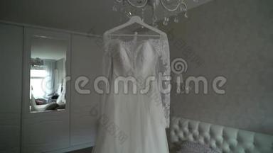 豪华婚纱挂在卧室里。 令人惊叹的新娘`<strong>蕾丝礼服</strong>的剪影。 早上的准备，开始